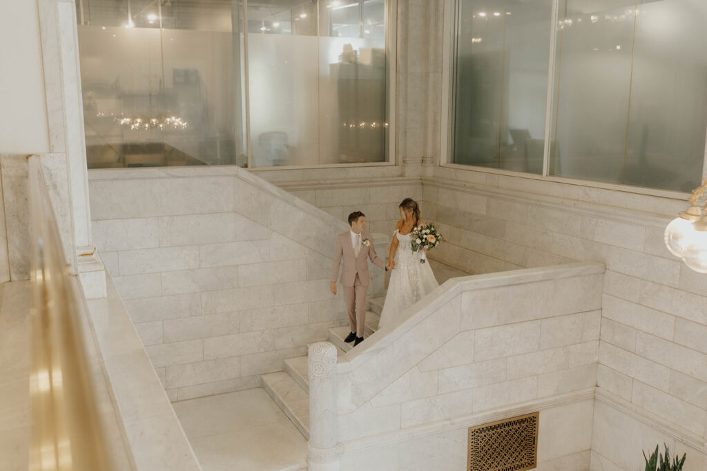 Bride-and-groom-walking-down-staircase-elegant-wedding-venue
