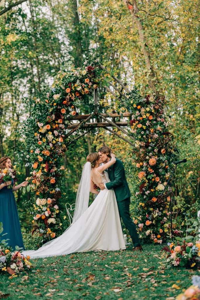 ceremony kiss autumn fall wedding floral arch modern woodland wedding