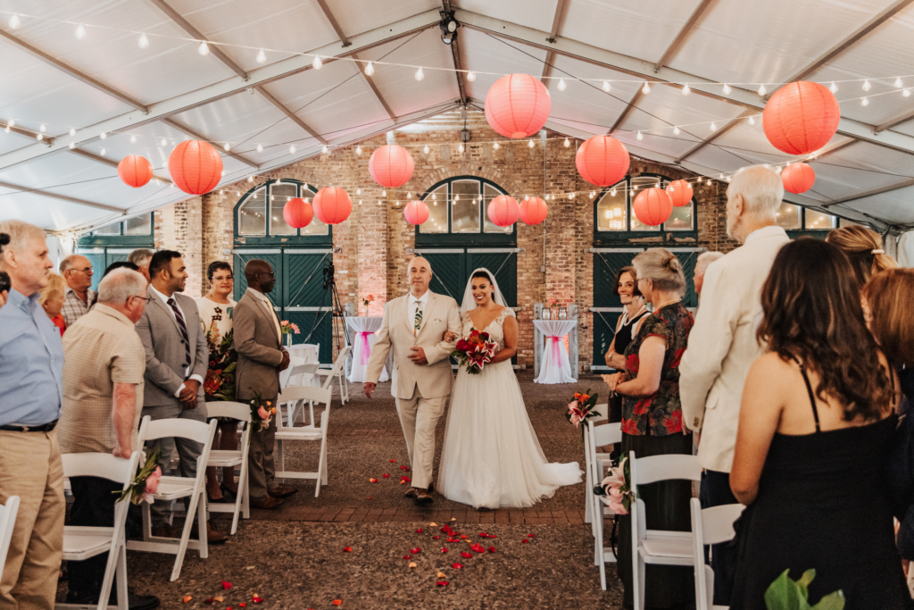 bride escorted by dad tent ceremony with pink hanging lanterns tropical wedding theme