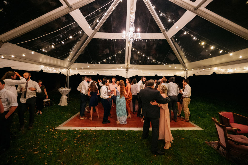 wedding guests dancing under clear top tent