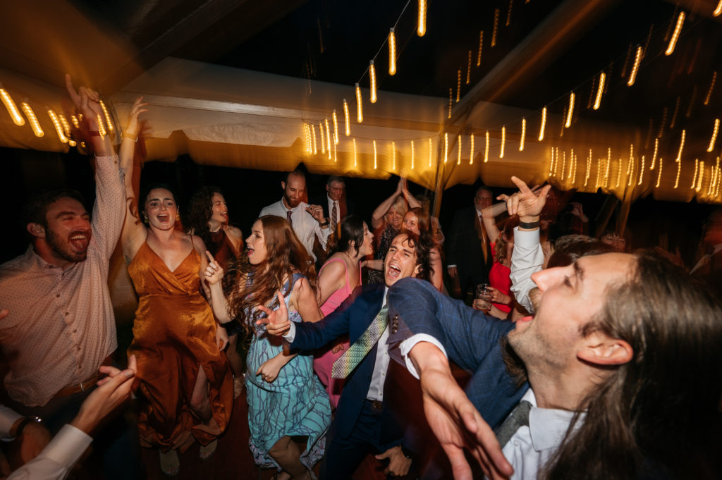 Wedding guests dancing under clear top tent