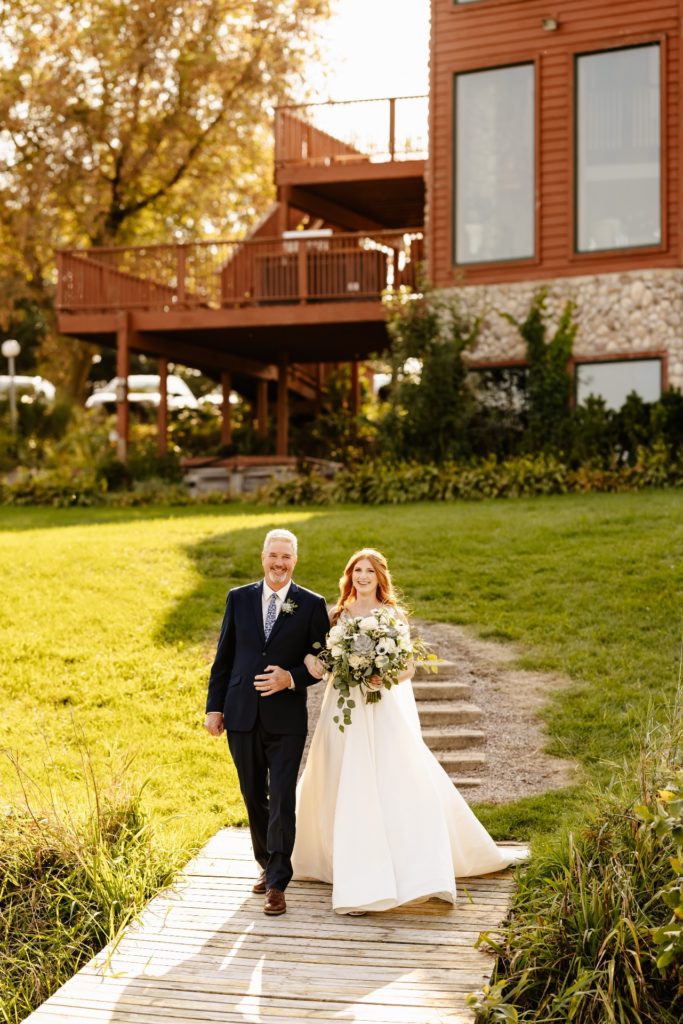 bride escorted by father down stairs at barn wedding venue