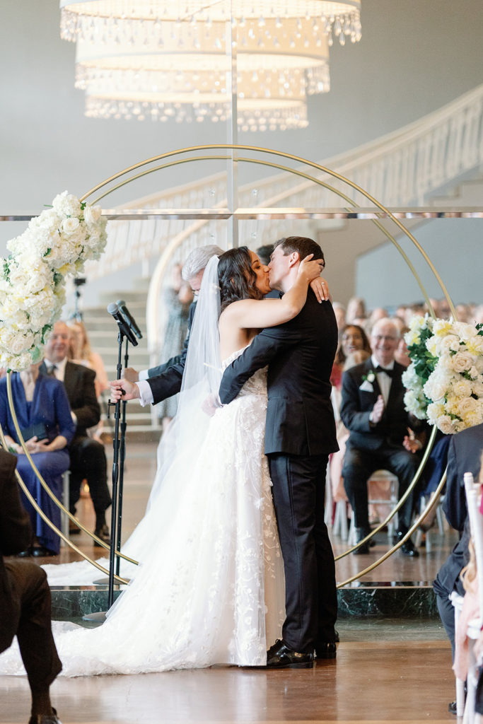 bride and groom ceremony kiss with round arch
