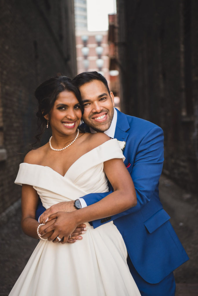 bride and groom hugging portrait, off the shoulder wedding dress, blue suit