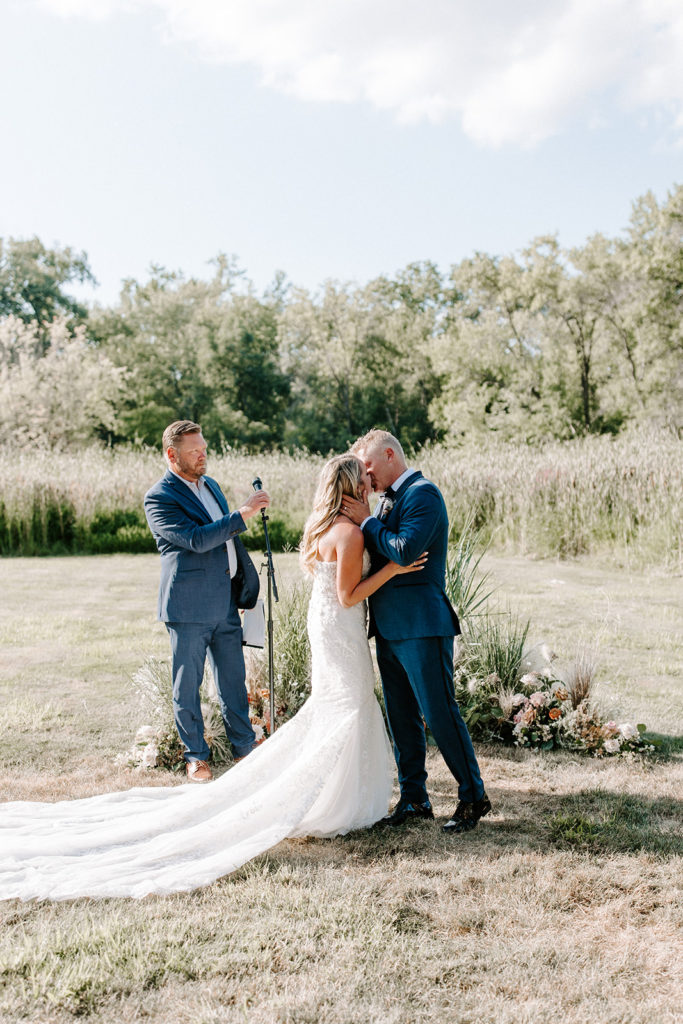 Summer outdoor ceremony bride and groom kiss at Cast & Cru wedding