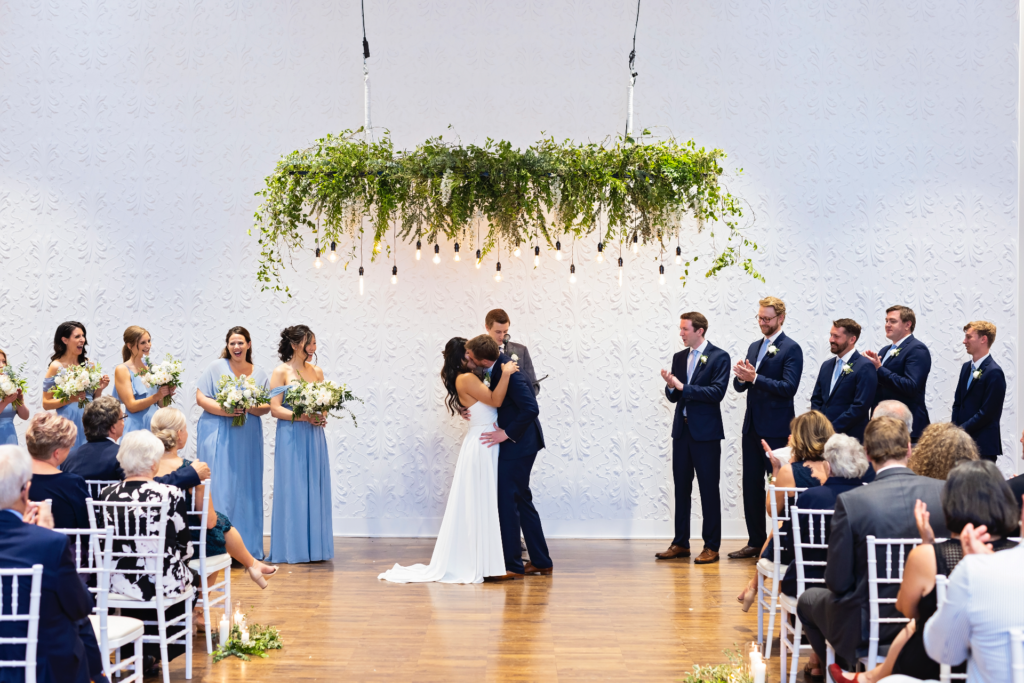 ceremony kiss against textured white wall 