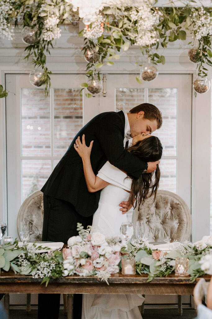 bride-groom-kiss-head-table-redeemed-farm-wedding