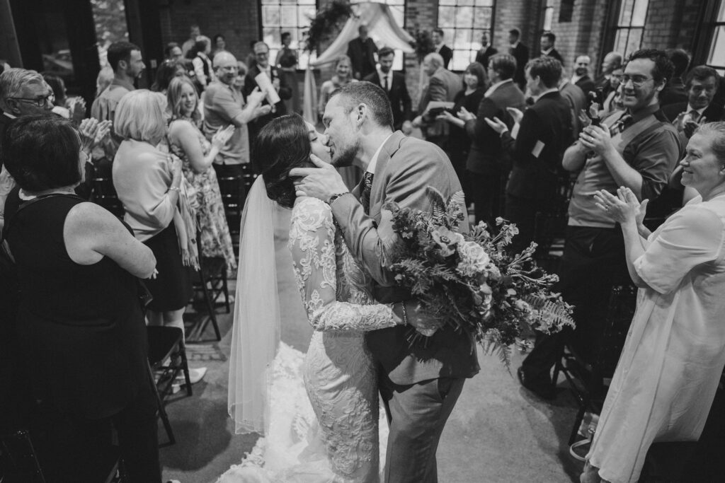bride and groom kiss during recessional in ceremony aisle