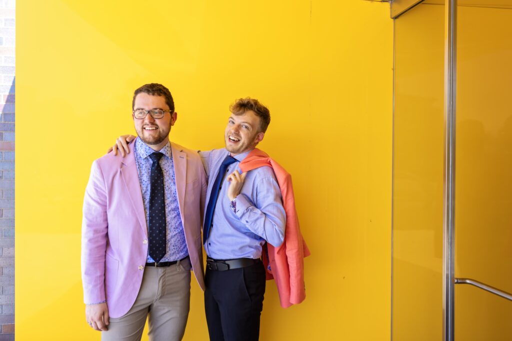 grooms wedding portrait in colorful suits against yellow wall at walker art center wedding