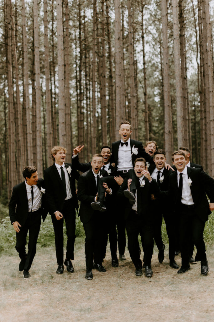 groomsmen in black suits fun portrait at Pinewood in MN