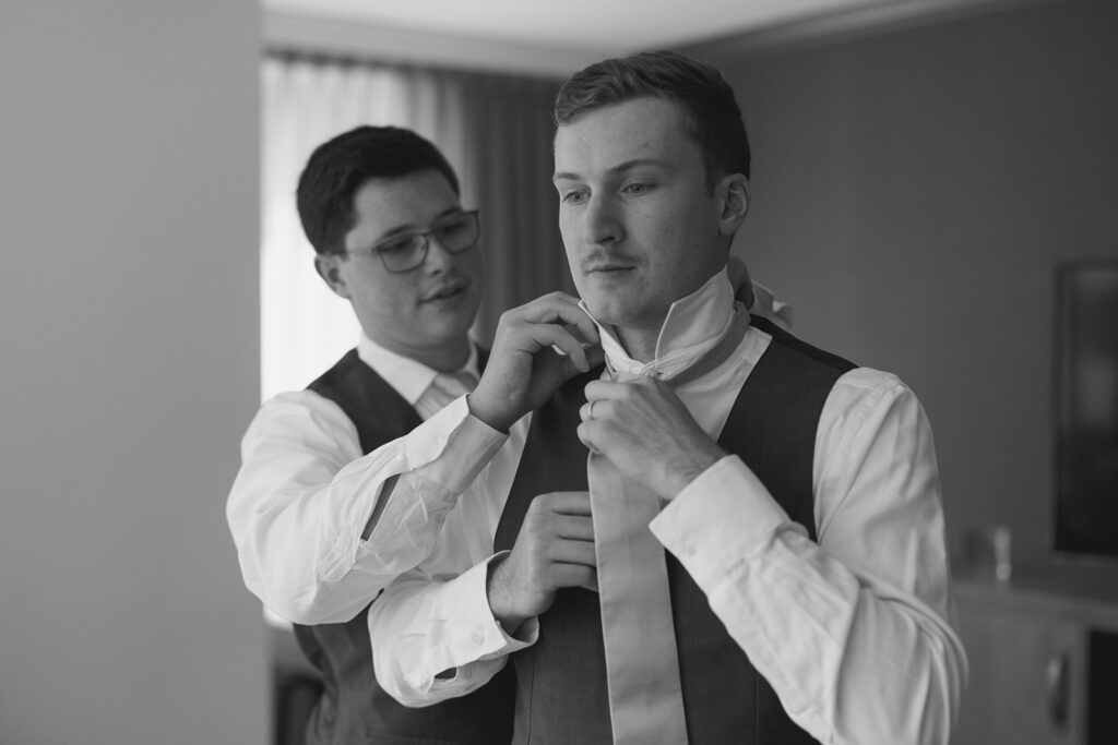 groom getting ready for downtown Minneapolis wedding with groomsmen tying tie 