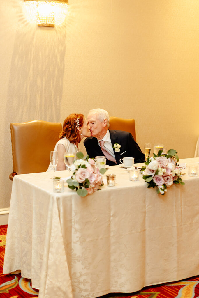 bride and groom kiss at sweetheart table 