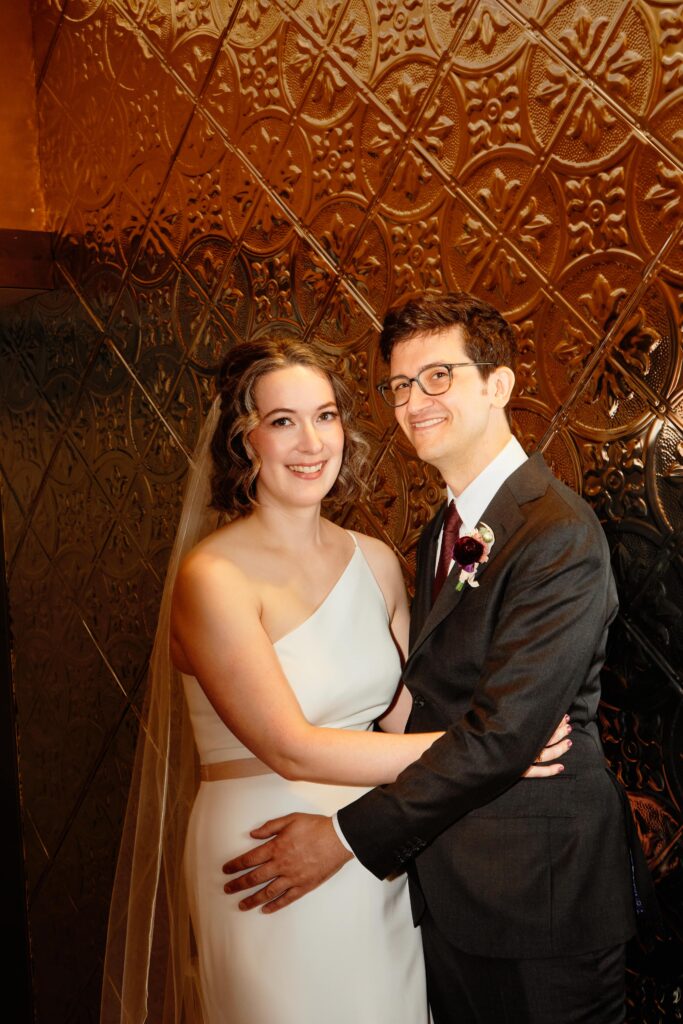 bride and groom portrait against textured wall