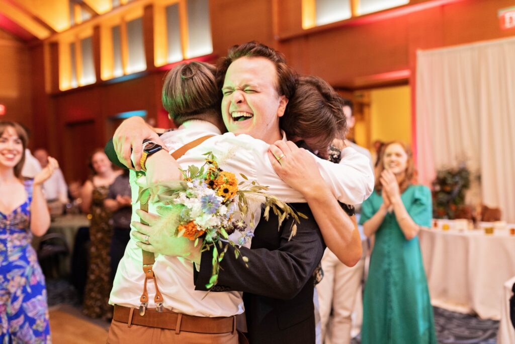 grooms hugging winner of bouquet toss