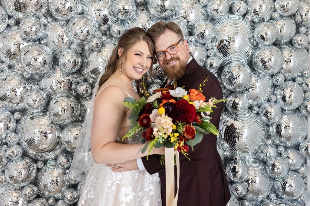 bride and groom portrait with disco ball wall