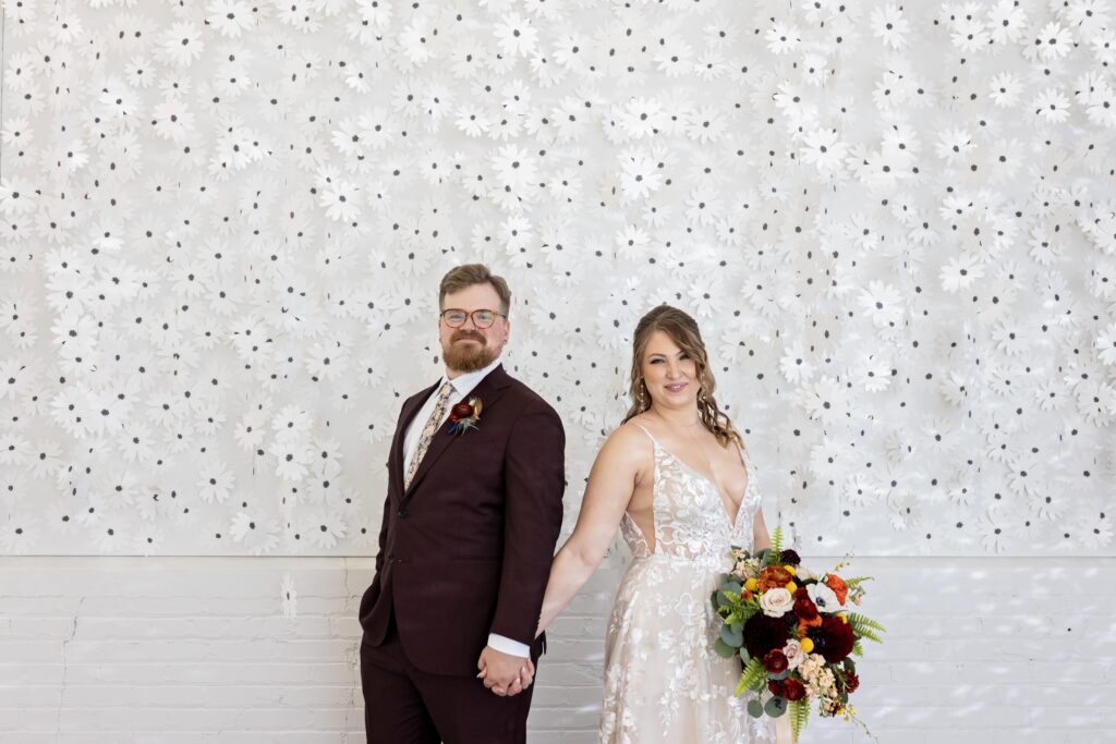 bride and groom portrait with floral wall at Urban Daisy