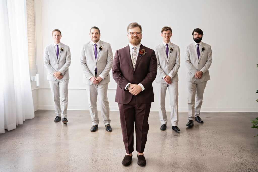 fun portrait with groomsmen in the background and groom in front