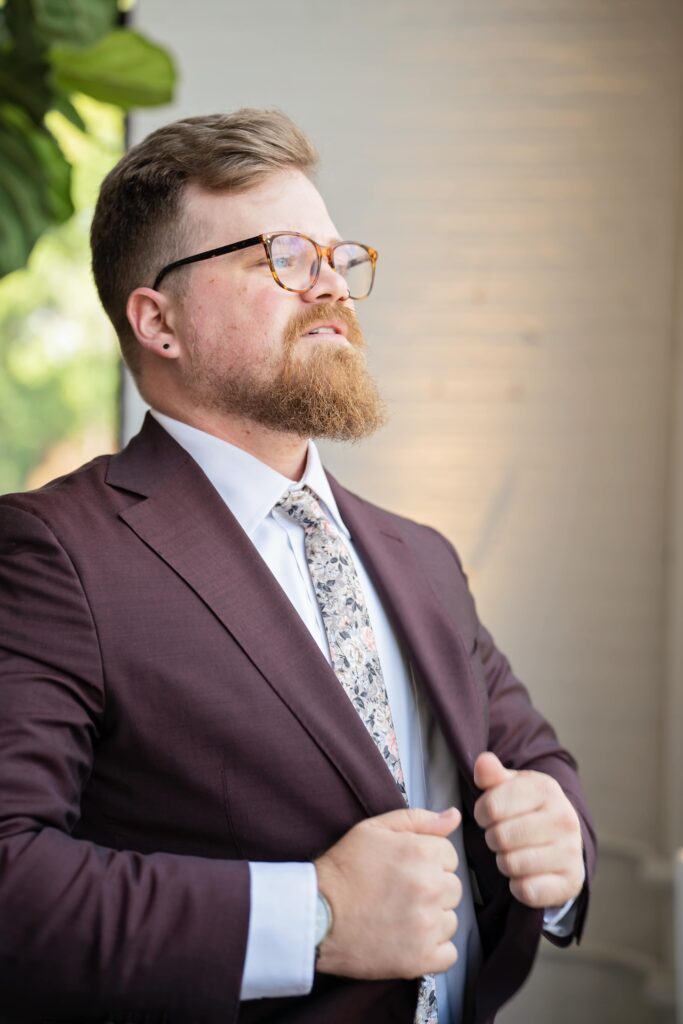 groom in maroon suit getting ready