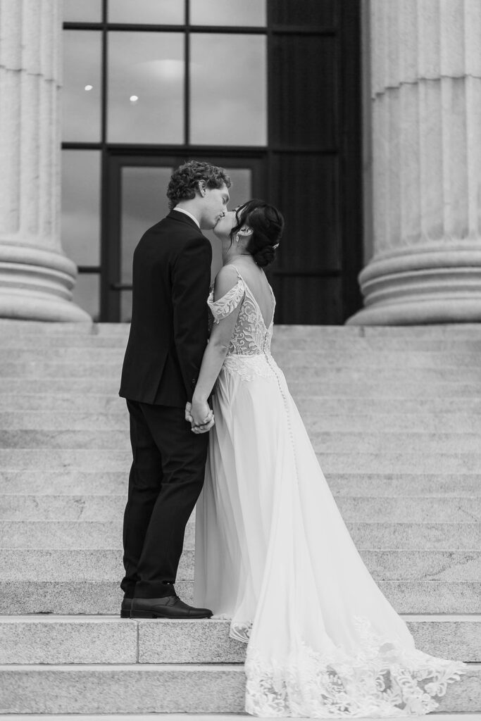 bride and groom kissing in front of art museum portrait