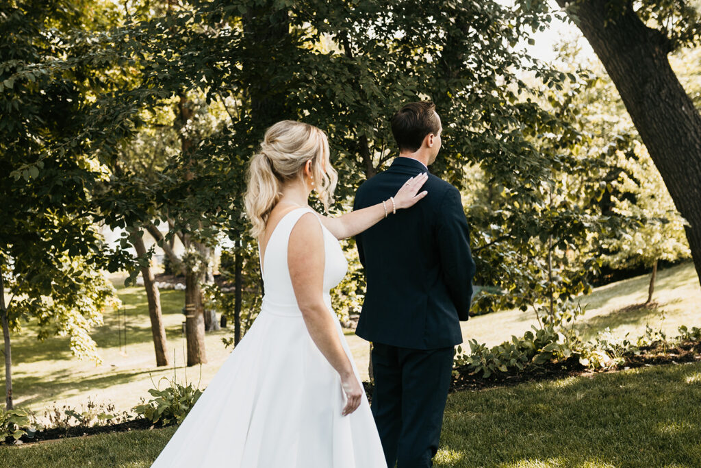 bride tapping on groom's shoulder for outdoor first look