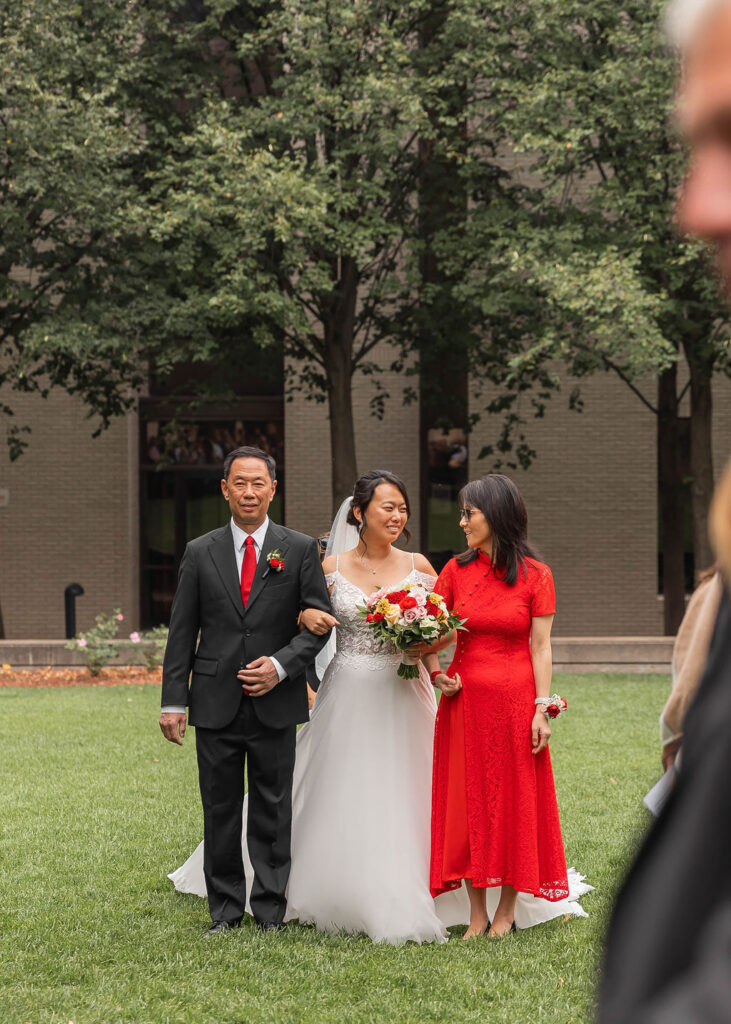 bride walking down the aisle with parents in outdoor ceremony