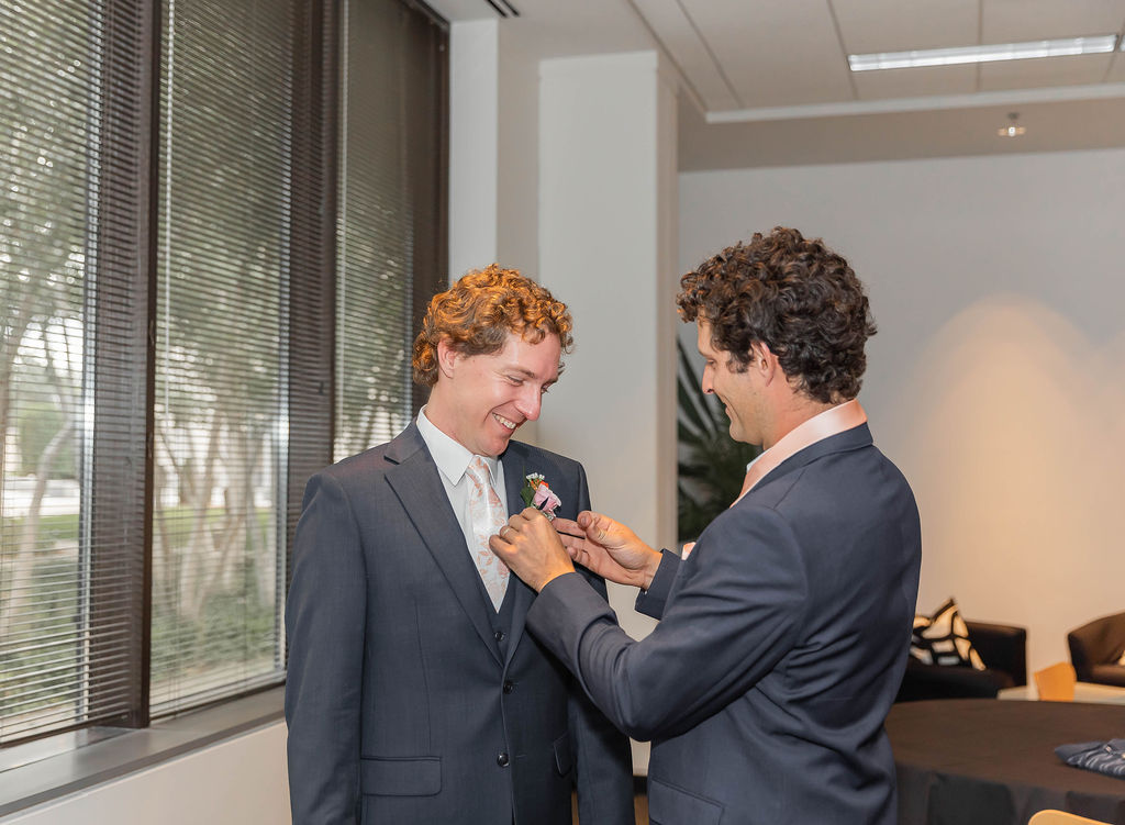 groomsman pinning boutonniere on groom