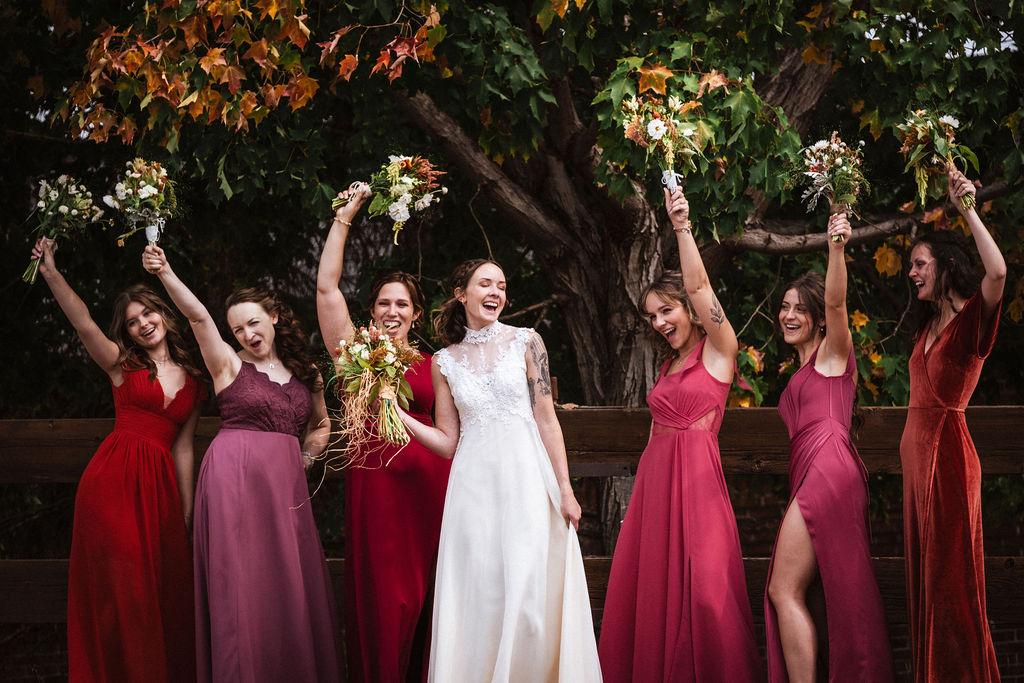 bride celebrating with bridesmaids wearing shades of ruby