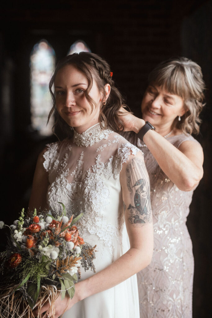 Bride putting on vintage wedding dress with mom