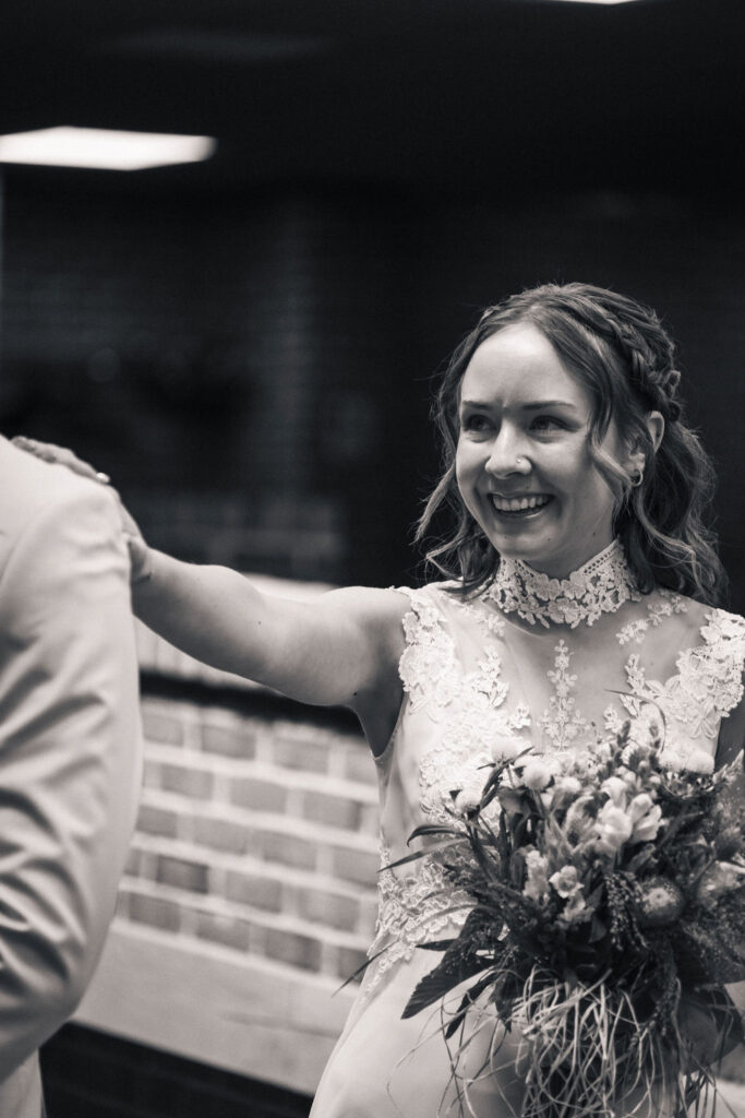 black and white photo of bride tapping groom for first look