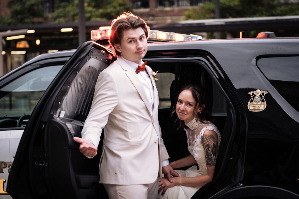 Funny wedding portrait of bride in police car