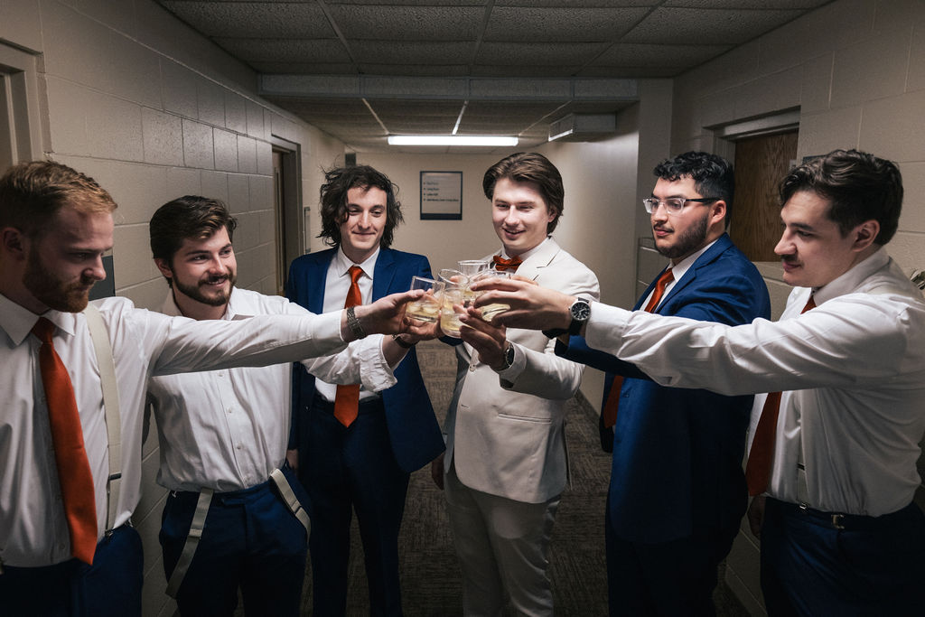 groomsmen cheers with groom while getting ready on wedding morning