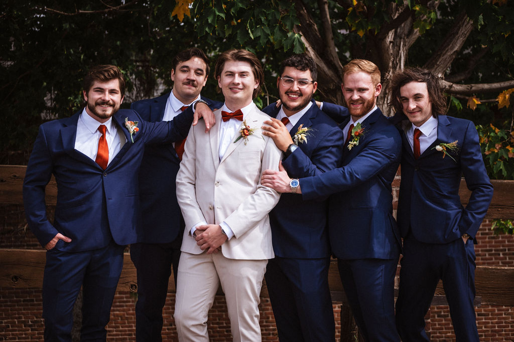 groom wearing cream suit with groomsmen wearing blue suits