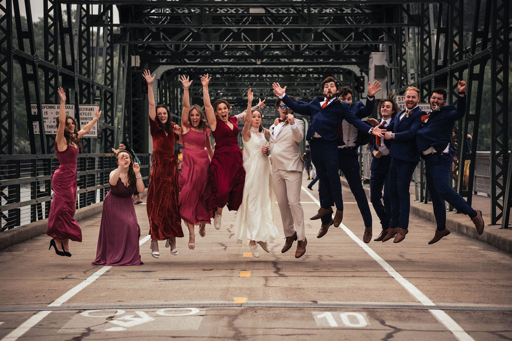 large wedding party jumping on bridge in Minneapolis