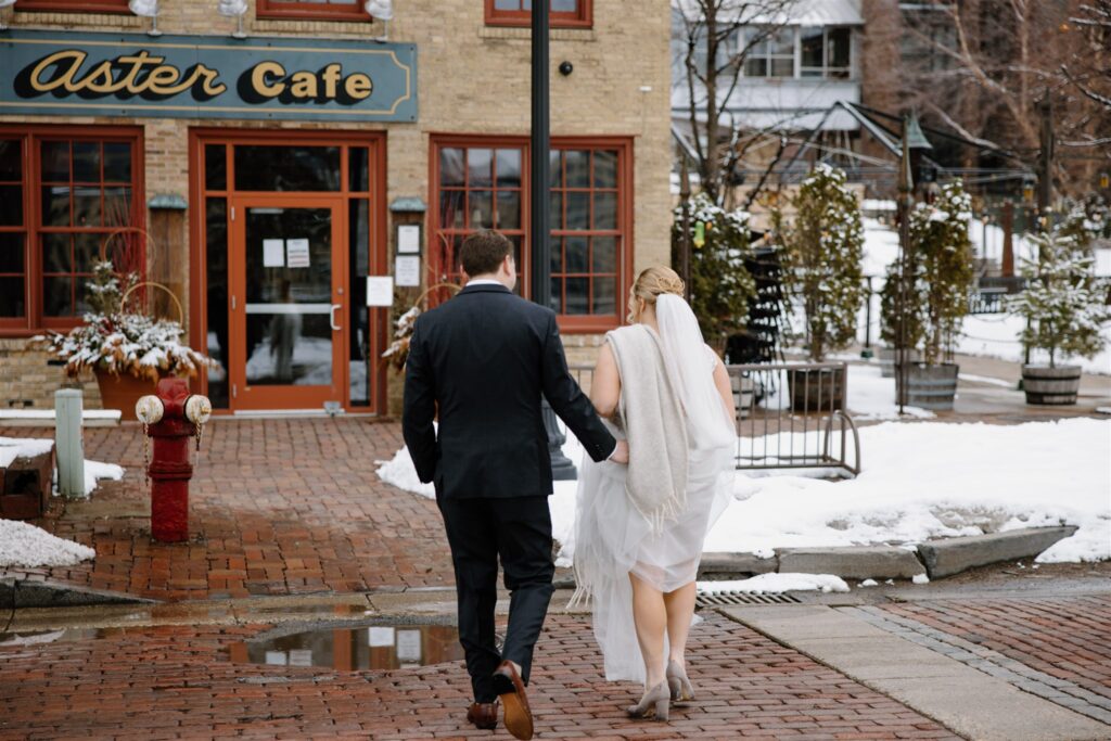 couple walking into Aster Cafe for their winter wedding