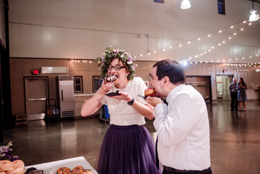 bride and groom eating donuts at wedding reception