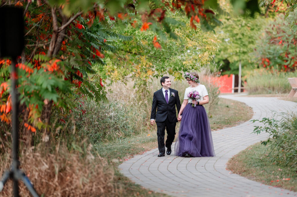 bride and groom walking down path to the ceremony site holding hands