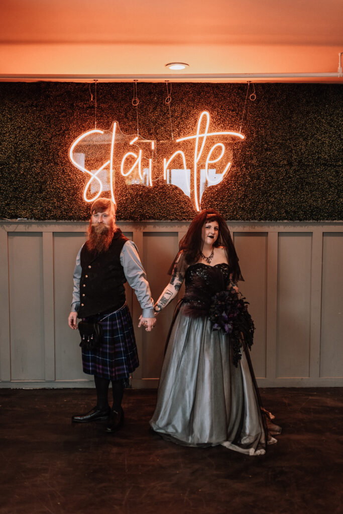 spooky bride and groom portrait in front of LED sign