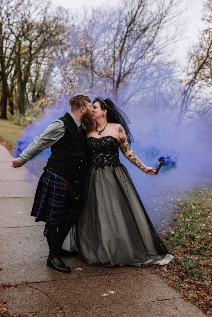 spooky wedding couple posing with purple smoke