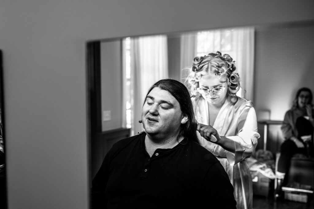 bride helping groom with hair wedding morning