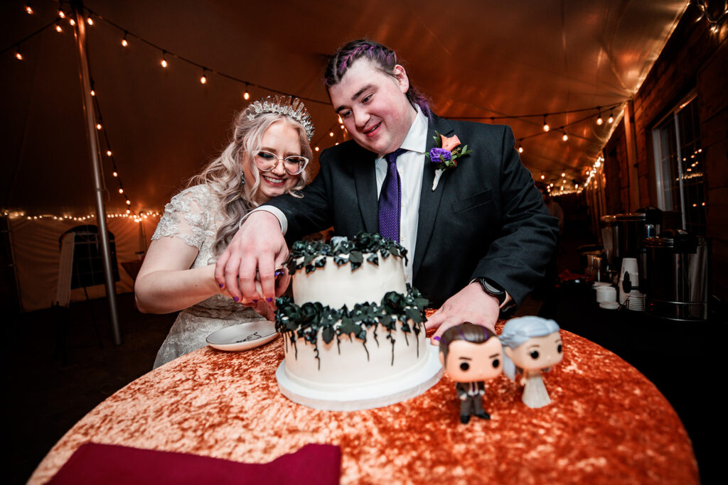 couple cutting black and white tiered wedding cake at October wedding at The Gardens