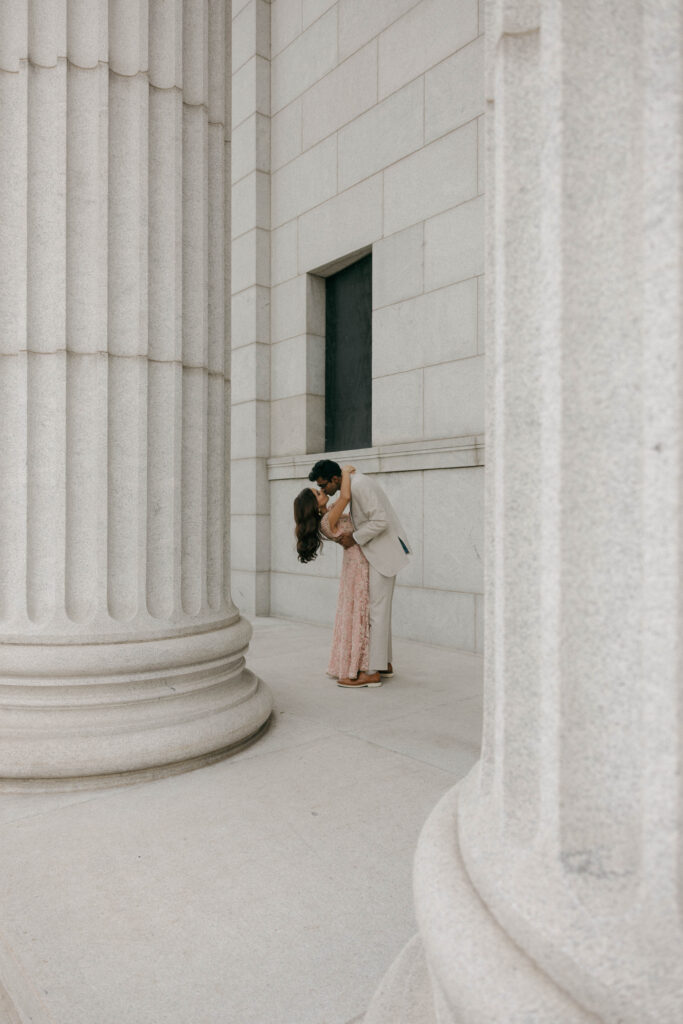 bride and groom kissing by giant pillars outside of museum