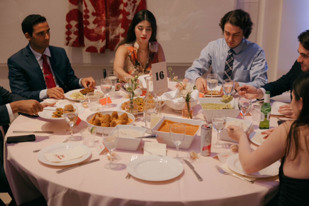 guests enjoying family style Indian cuisine at wedding reception