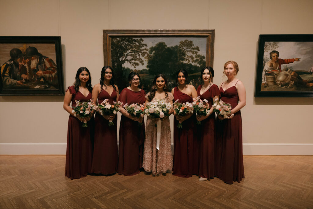 bridesmaids in red dresses posing in art gallery