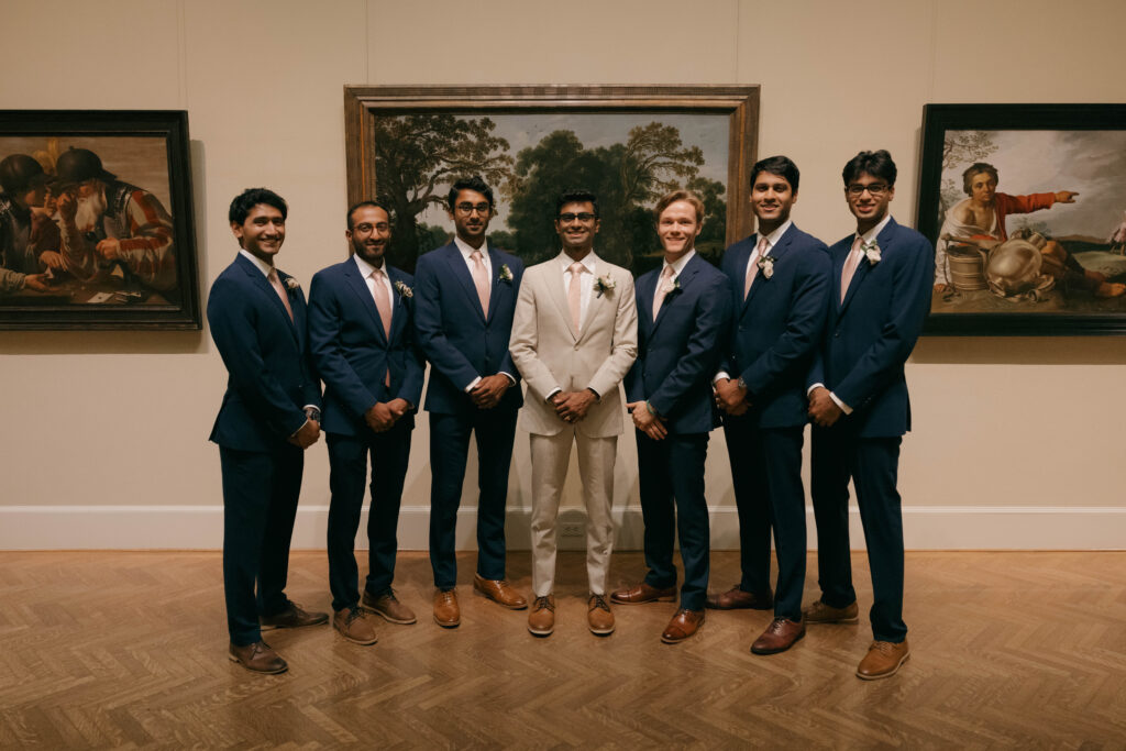 groomsmen in blue suits posing in art gallery