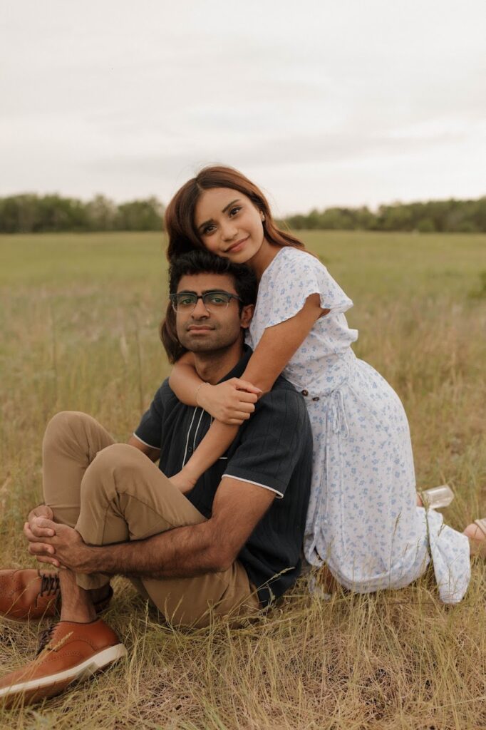 bride hugging groom sitting in grass engagement photo