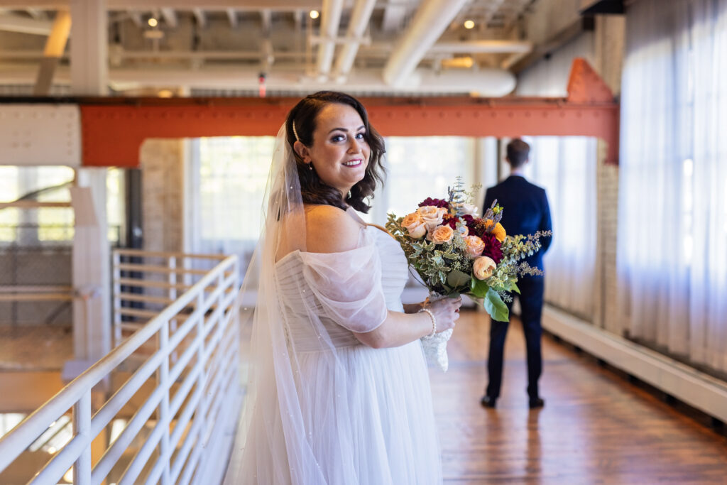 bride first look with groom holding large bouquet