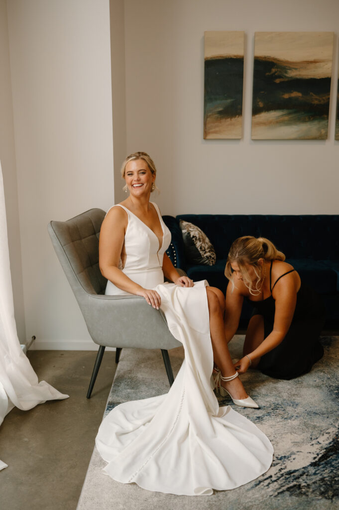 maid of honor helping bride put heels on