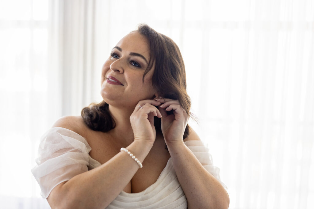 bride getting ready putting in earrings wedding morning