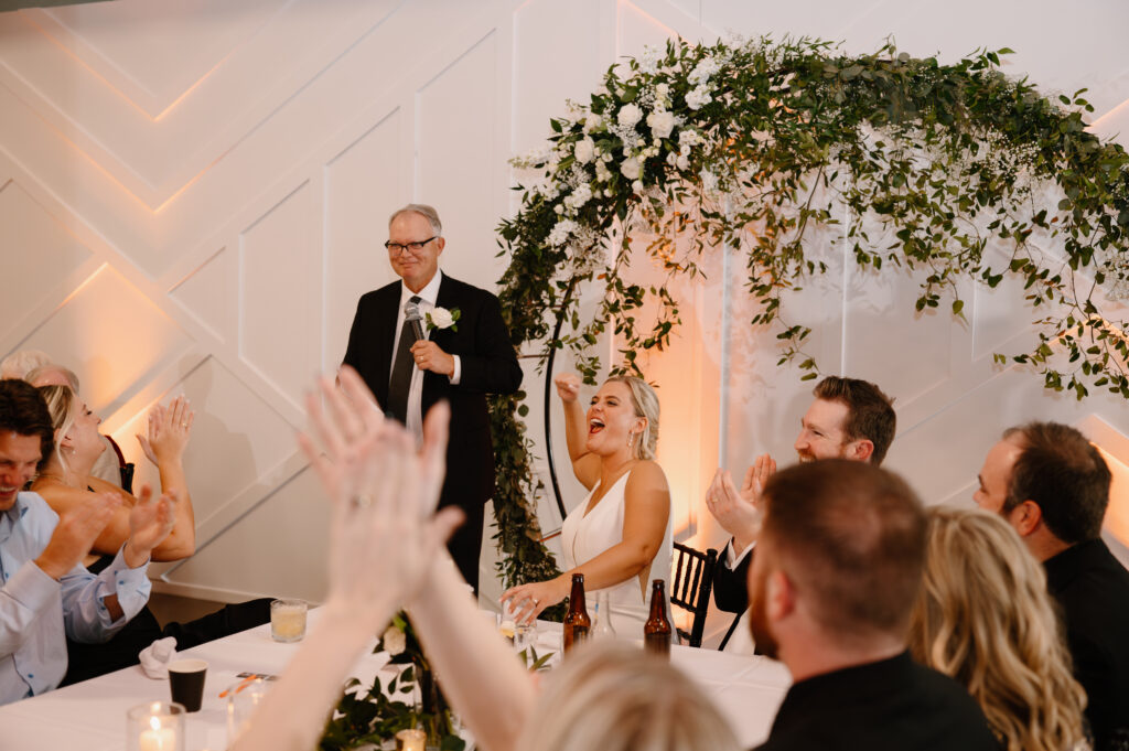 guests hyping up bride's father during speech