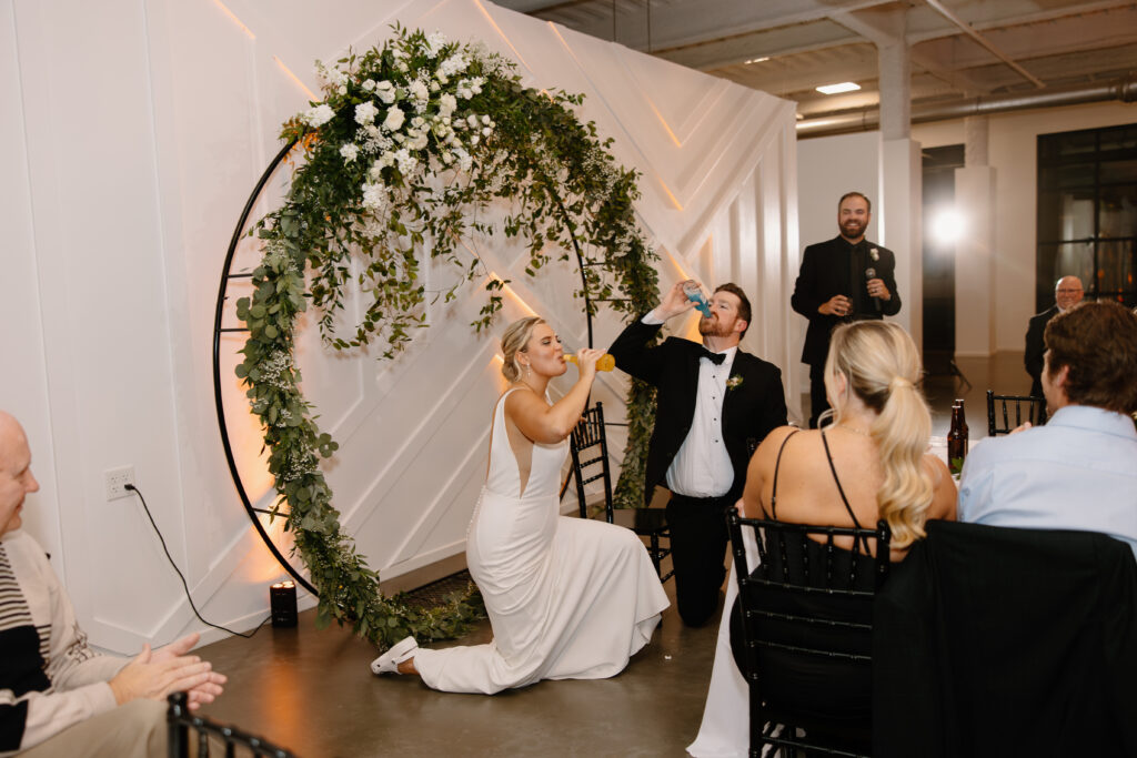 bride and groom take a knee after being iced and drink